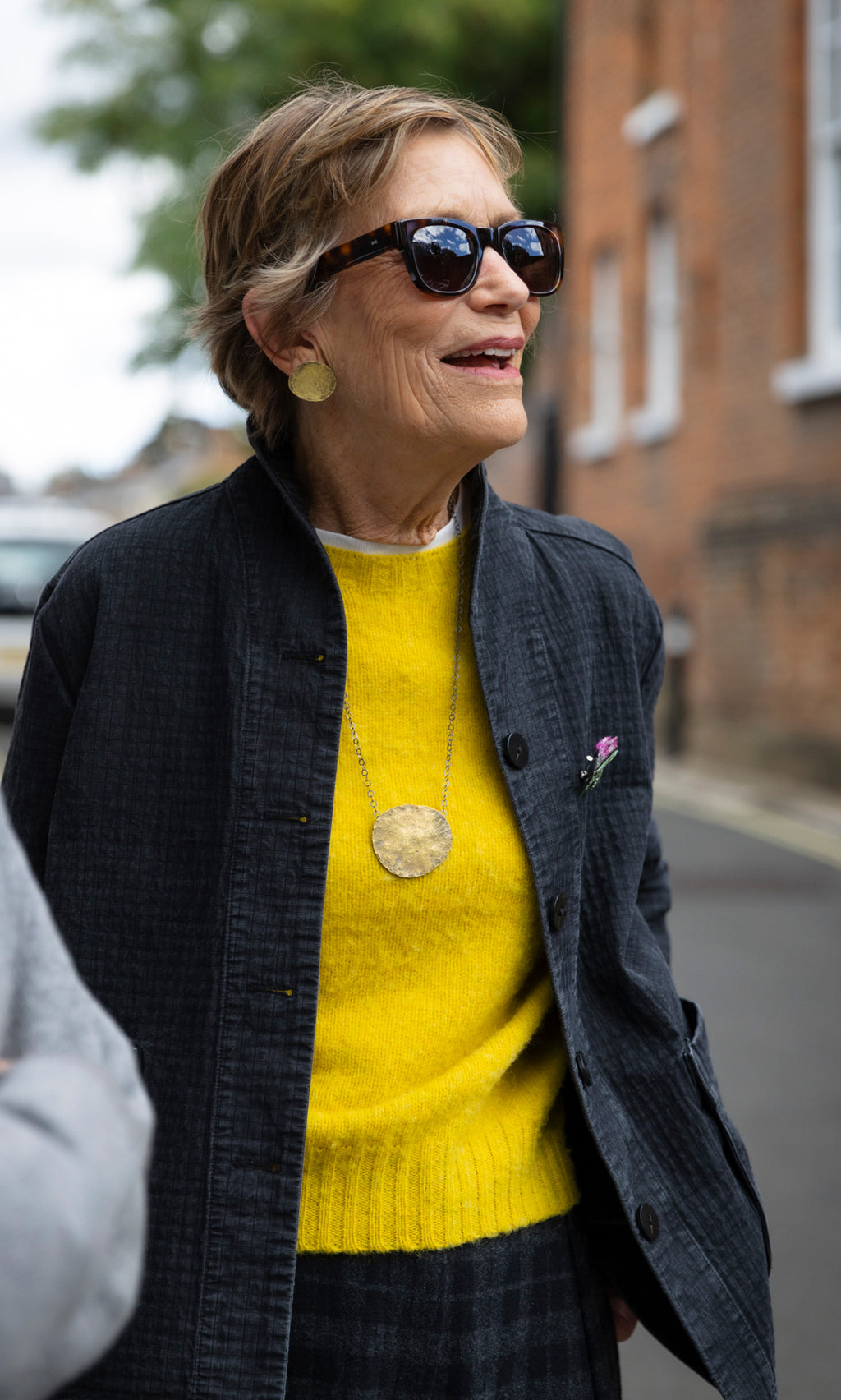 Plümo  The Cressa Necklace features a woman wearing a long sterling silver chain with a large, textured gold brass pebble pendant.