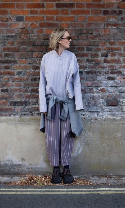 Plümo  A person wears a Bennett Blouse - Smoke with matching trousers and a sweater tied around their waist.