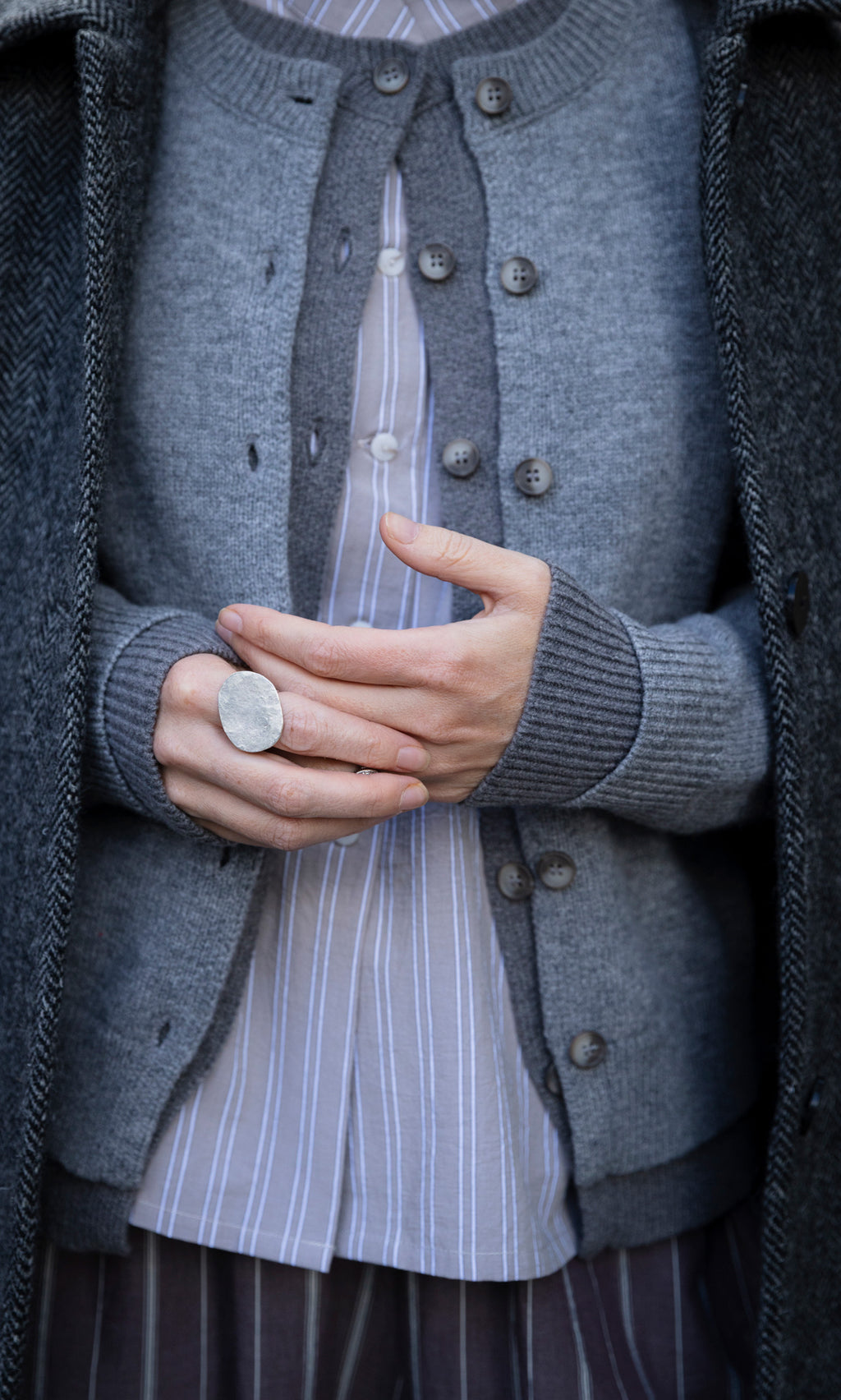 Plümo  A person wearing a large, textured handmade Eco Silver Pebble ring on their finger.