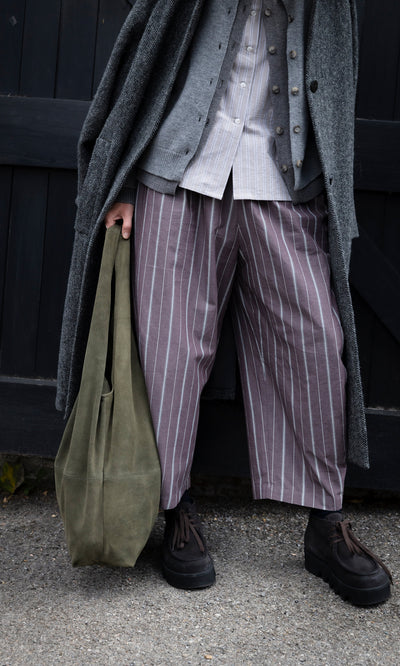 Plümo  Person wearing Butoni Pants - Liquorice, a button-down, cardigan, long coat, and dark platform shoes.