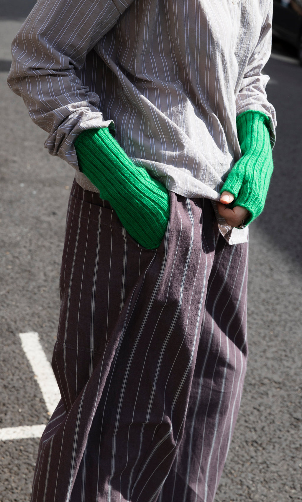 Plümo  A person wearing vibrant green Green Wristwarmers, featuring a fingerless, ribbed design.