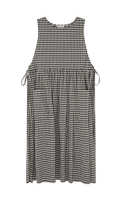 Plümo- Apron Dress - Gingham: Sleeveless black-and-white check dress with side bows, pockets, and gathered waist.