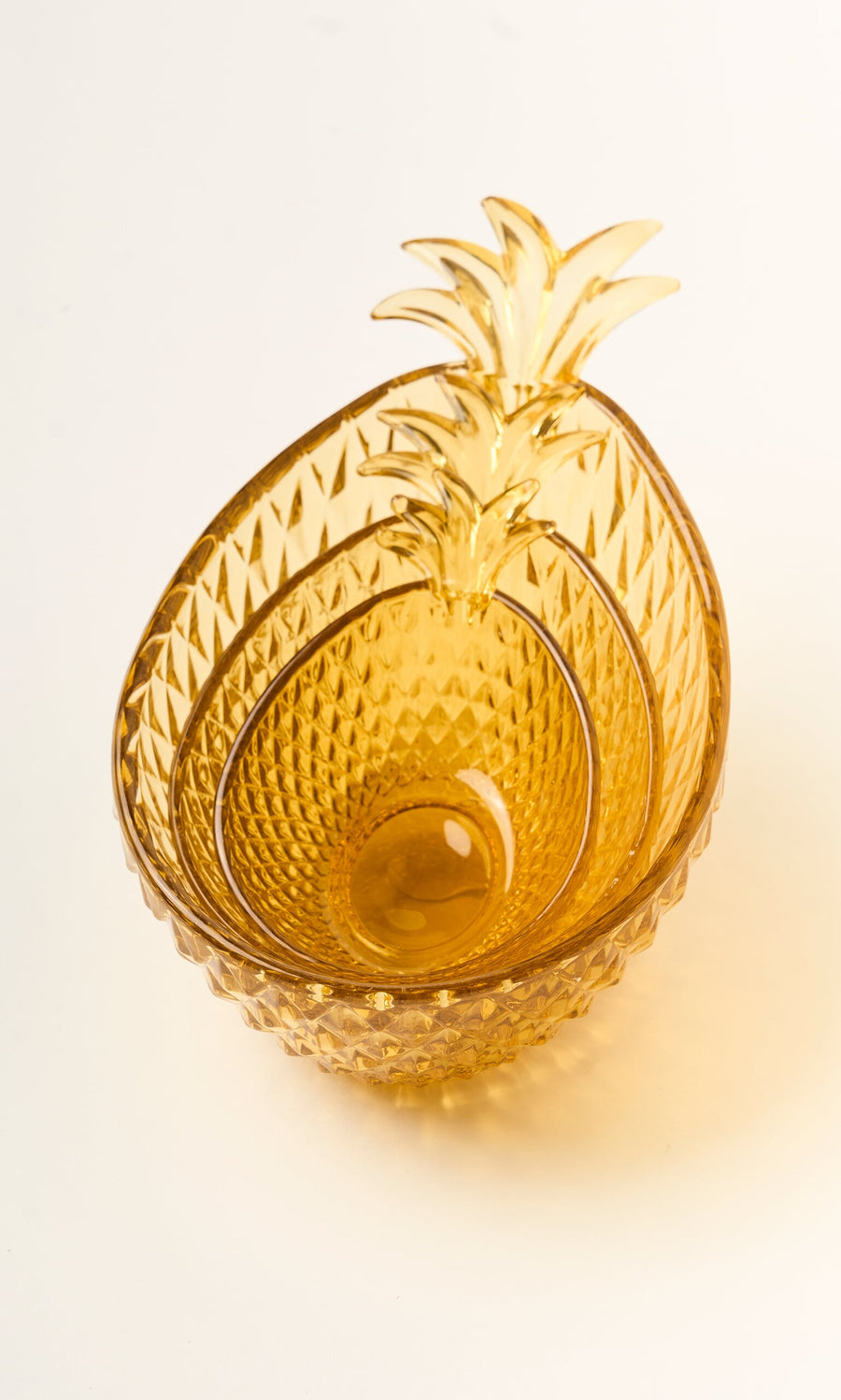 Plümo- Set of 3 amber yellow Glass Pineapple Bowls, nested together on a white surface.