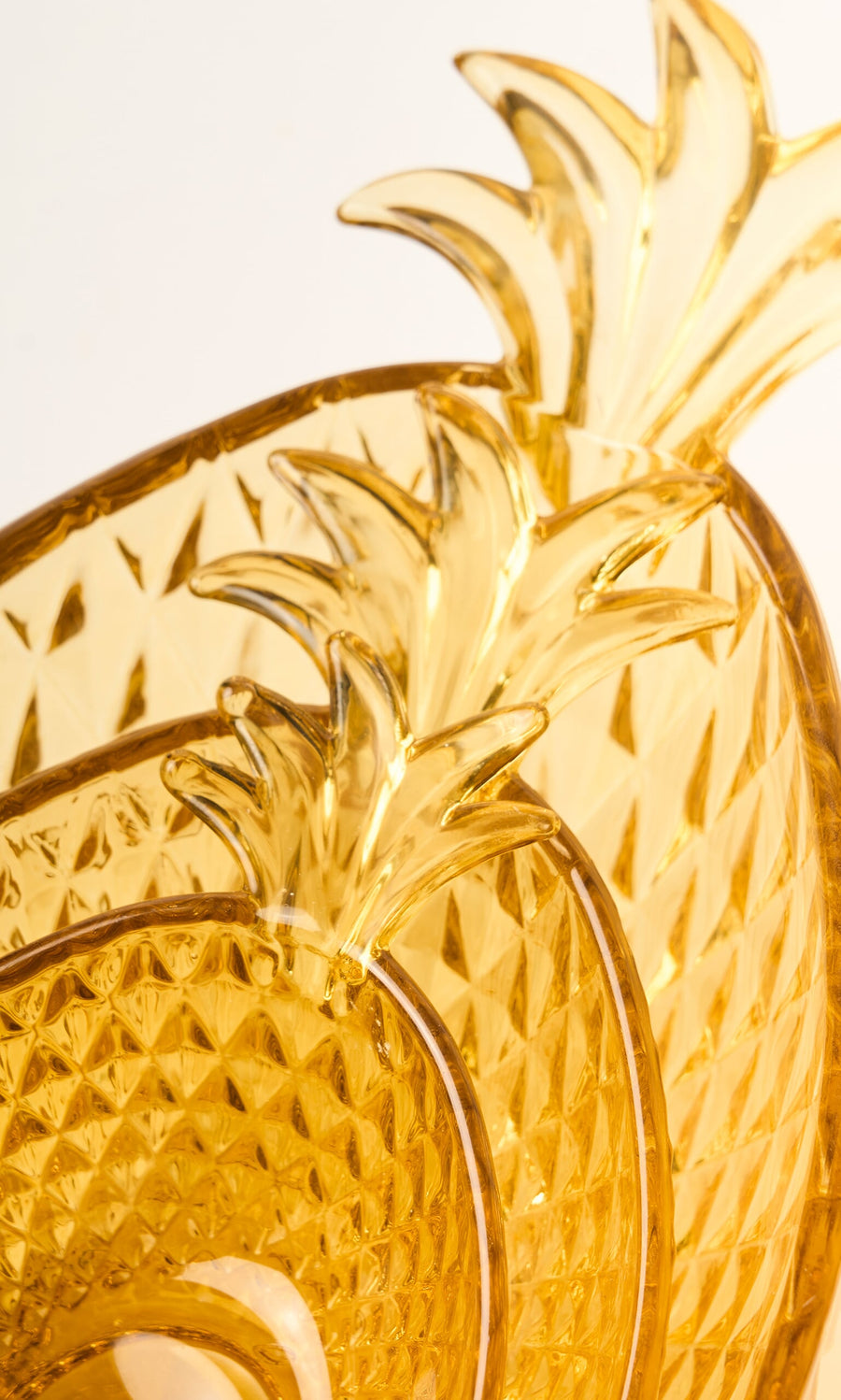 Plümo- Set of three Glass Pineapple Bowls, stacked and crafted from textured amber yellow glass with leafy tops.