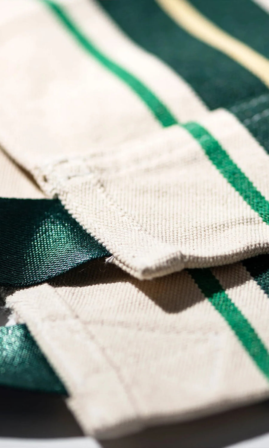 Plümo- Close-up of layered cream fabric with green stripes from the Green Stripe Folding Bag.