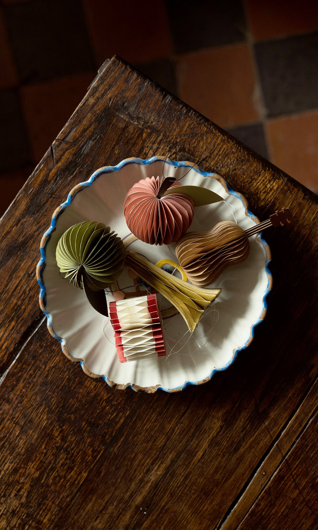 Plümo- A plate on a wooden table holds the Honeycomb Instruments (set of 3) for festive decorating.