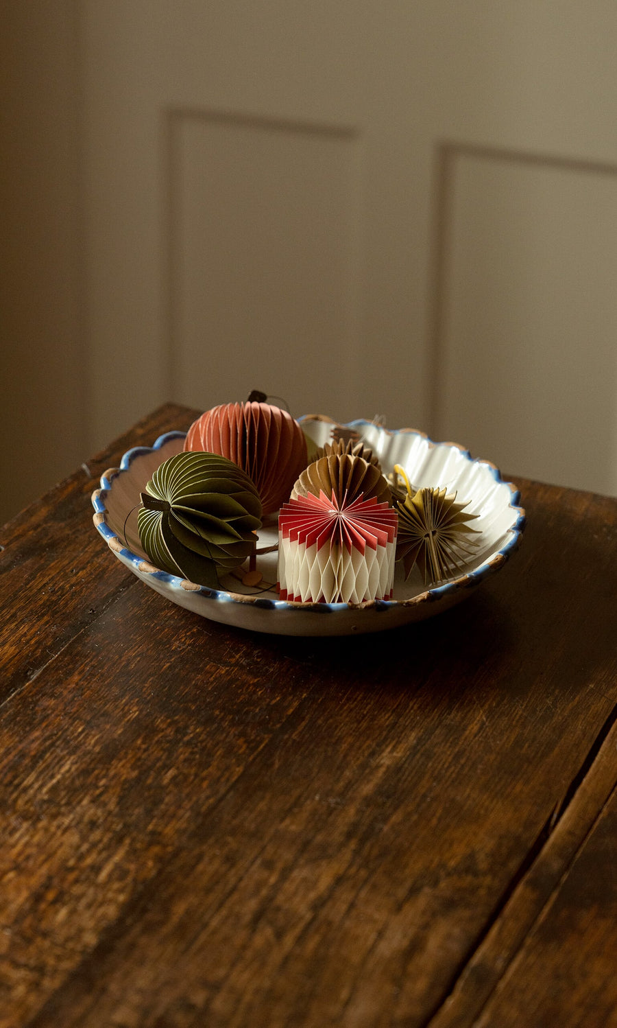 Plümo- A white scalloped bowl holds Honeycomb Apples (set of 2) on a wooden table in soft lighting.