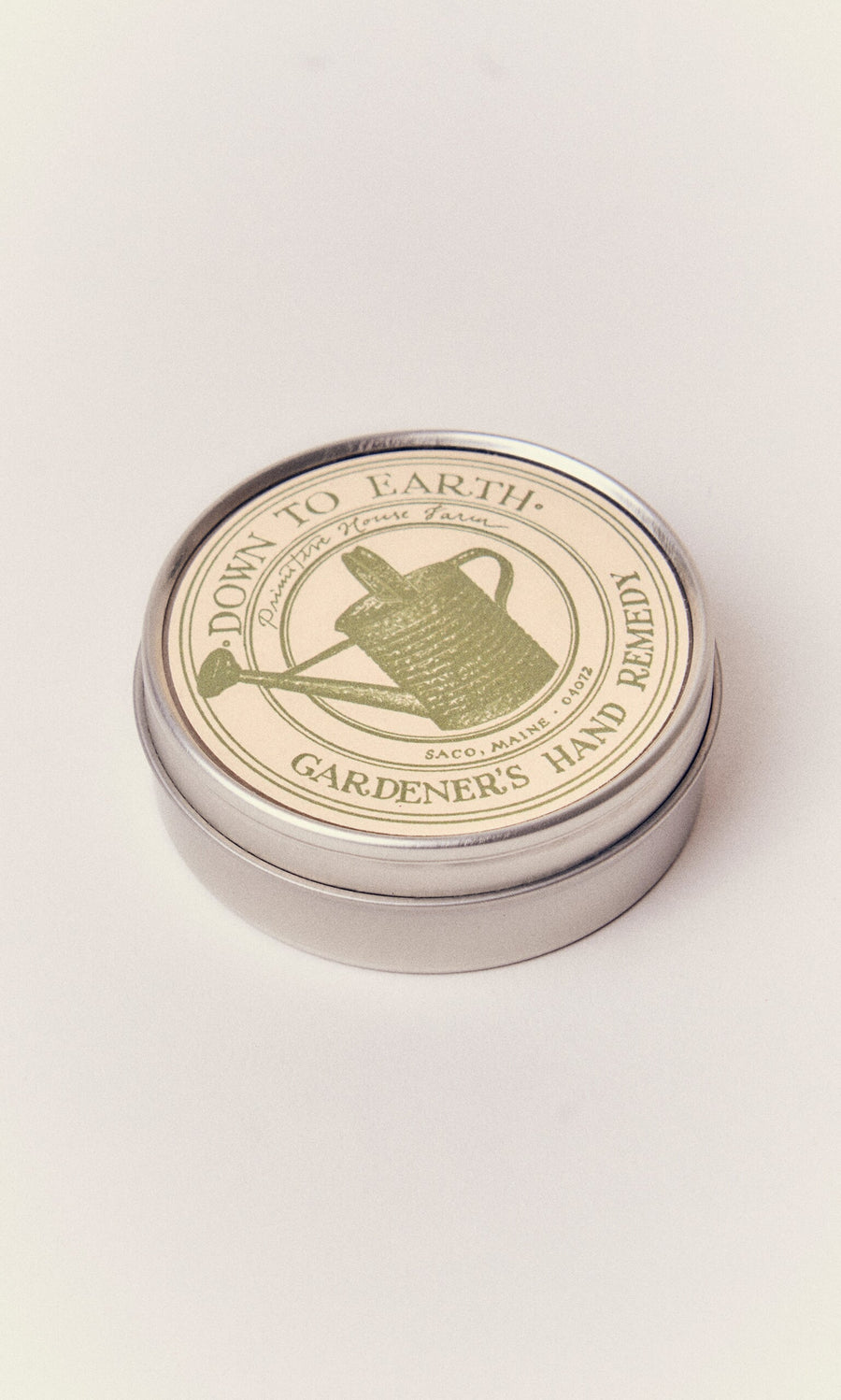Plümo- A round tin of Gardener's Hand Remedy, nourishing hand balm, handcrafted in Maine with a watering can label.