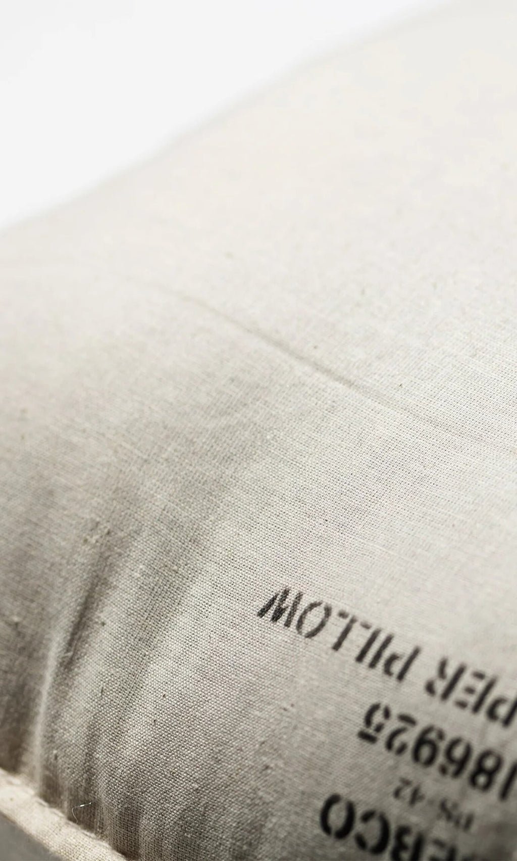 Plümo- Close-up of the Handbag Shaper Pillow - Rectangle in beige, showing partially visible black printed text.