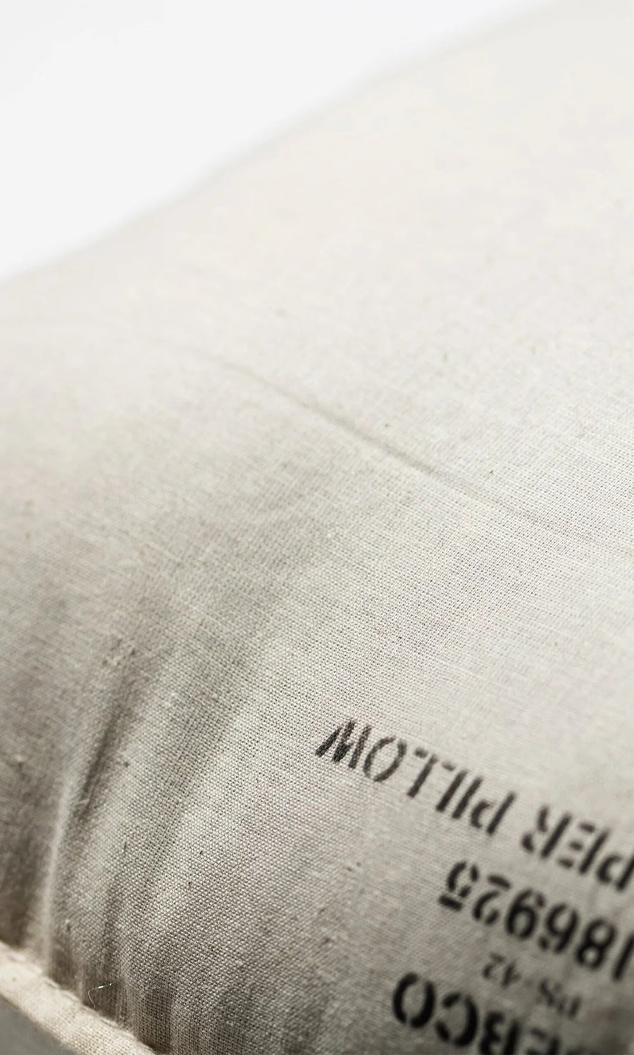 Plümo- Close-up of a white Handbag Shaper Pillow - Cylinder with partially visible black printed text on the fabric.