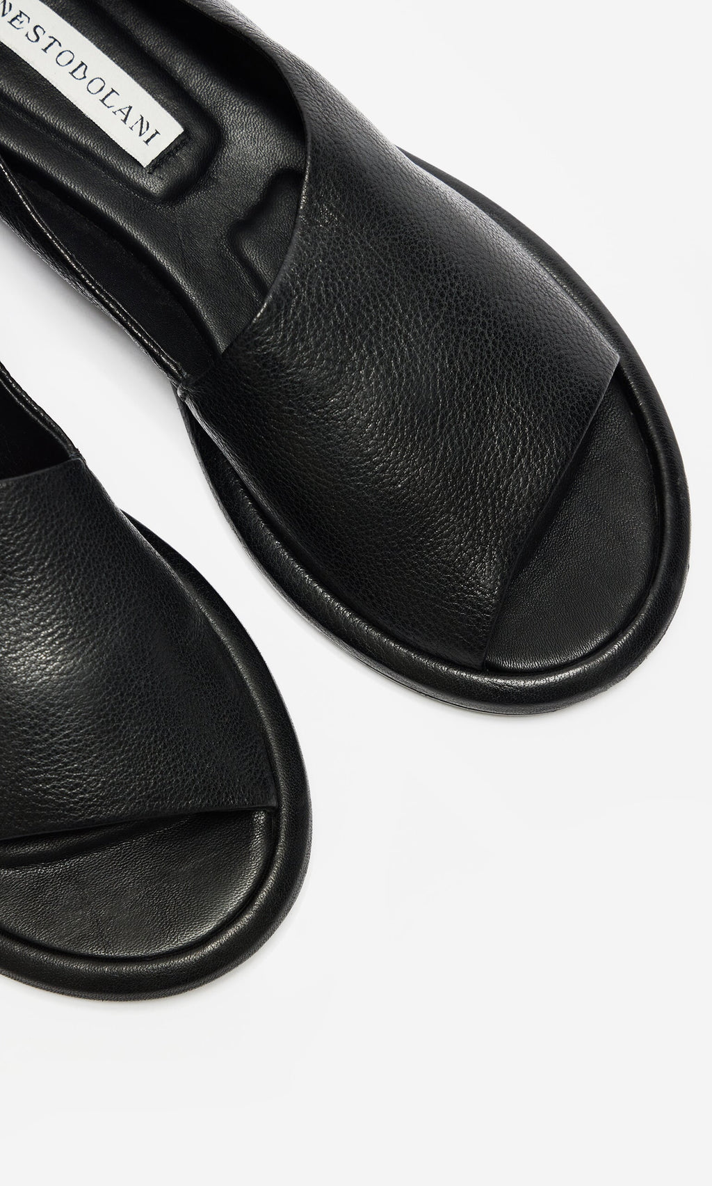 Plümo- Close-up of black, open-toe Hawke Sandals, artisan-made leather slides on a white background.