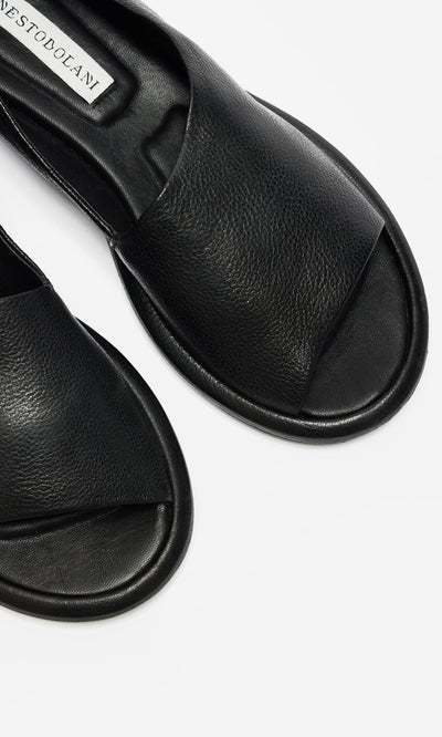 Plümo- Close-up of black, open-toe Hawke Sandals, artisan-made leather slides on a white background.