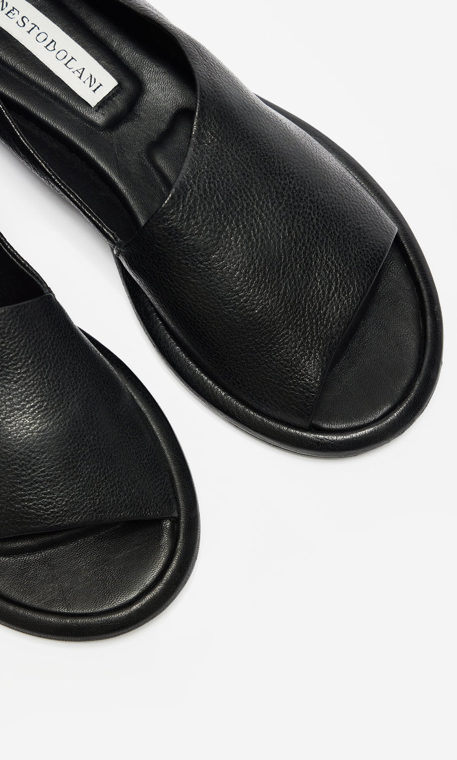 Plümo- Close-up of black, open-toe Hawke Sandals, artisan-made leather slides on a white background.