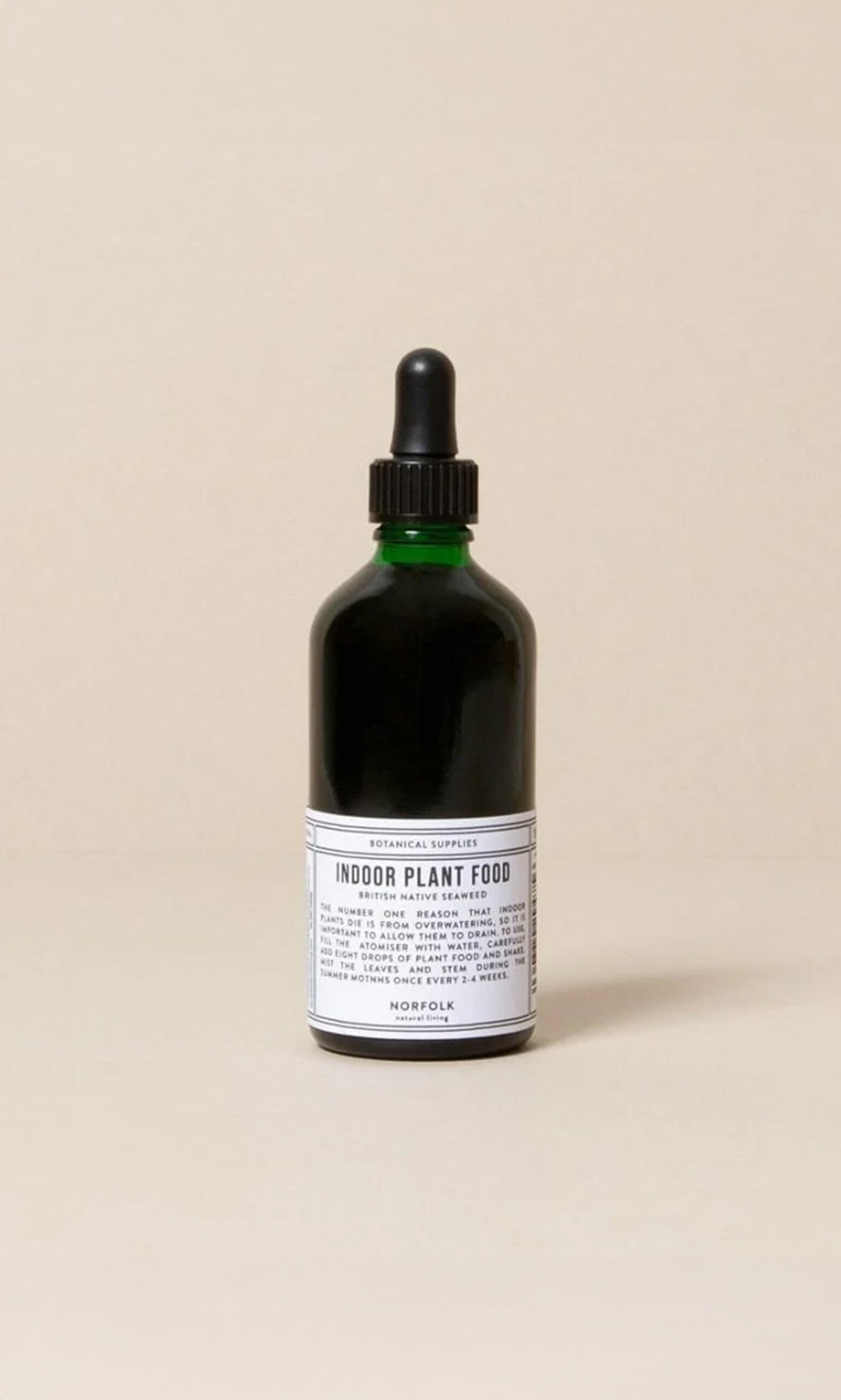 Plümo- A green glass bottle of Indoor plant food with a black dropper cap and white label on a neutral background.