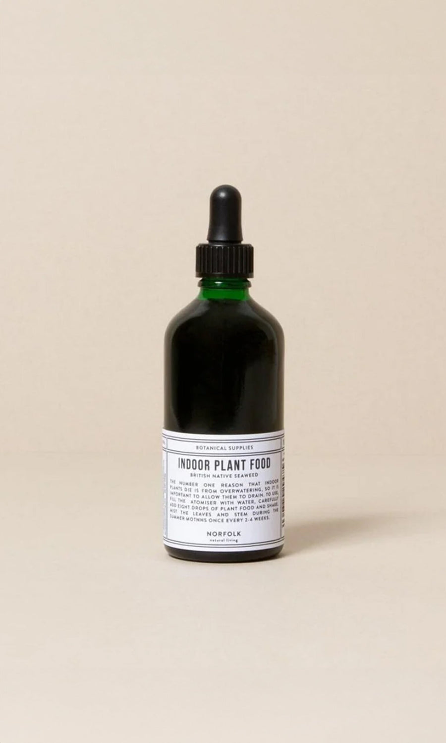 Plümo- A green glass bottle of Indoor plant food with a black dropper cap and white label on a neutral background.