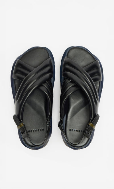 Plümo- Korra Sandals: black, cushioned open-toe sandals with criss-cross straps, shown on a white background.