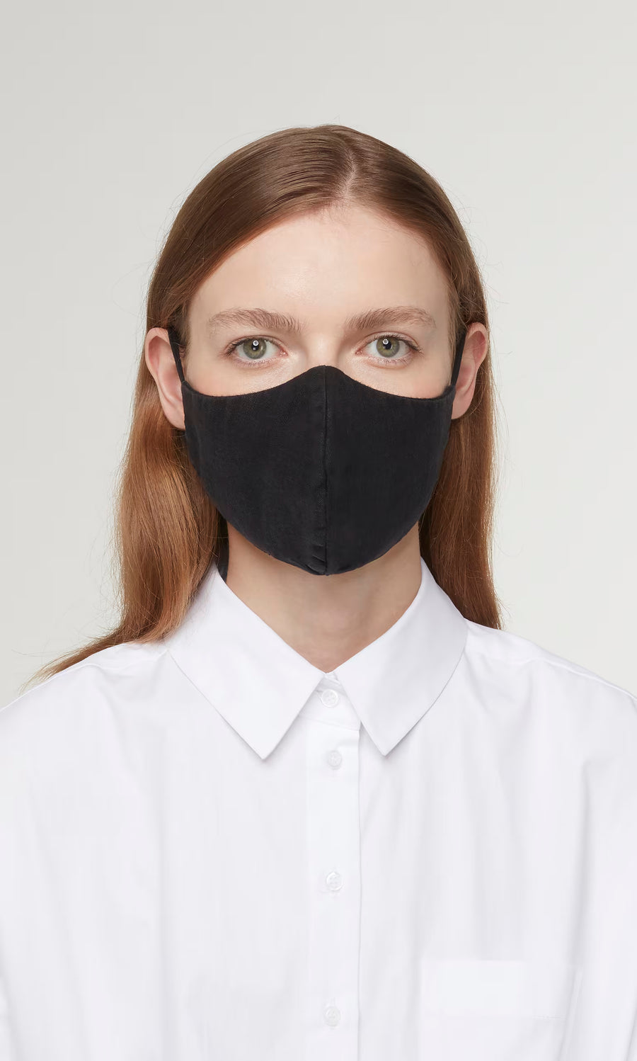 Plümo  Person with long brown hair in a white shirt wears the Organic Linen Mask - Black, looking directly at the camera.