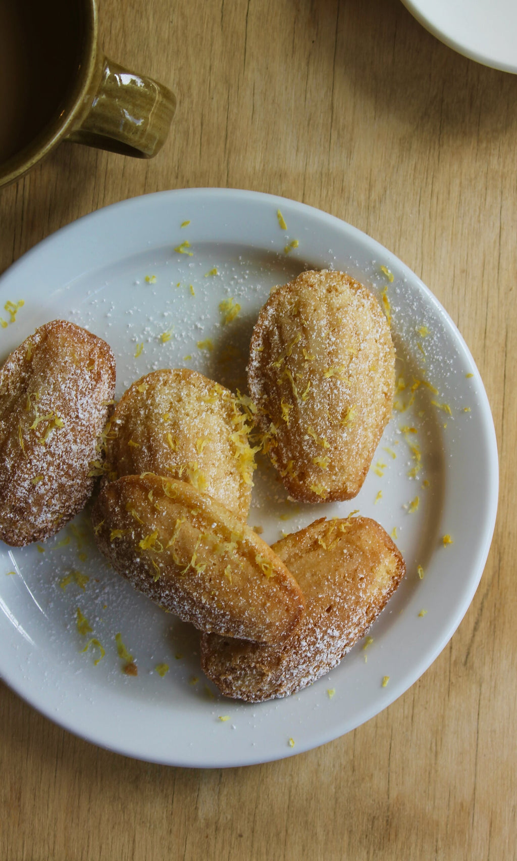 Plümo- Five madeleines with powdered sugar and lemon zest, inspired by Midweek Recipes By Jess Elliott Dennison.