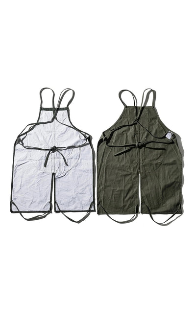 Plümo- Two Lumberjack Aprons, sleeveless with black straps, in dark green fabric, laid flat side by side.