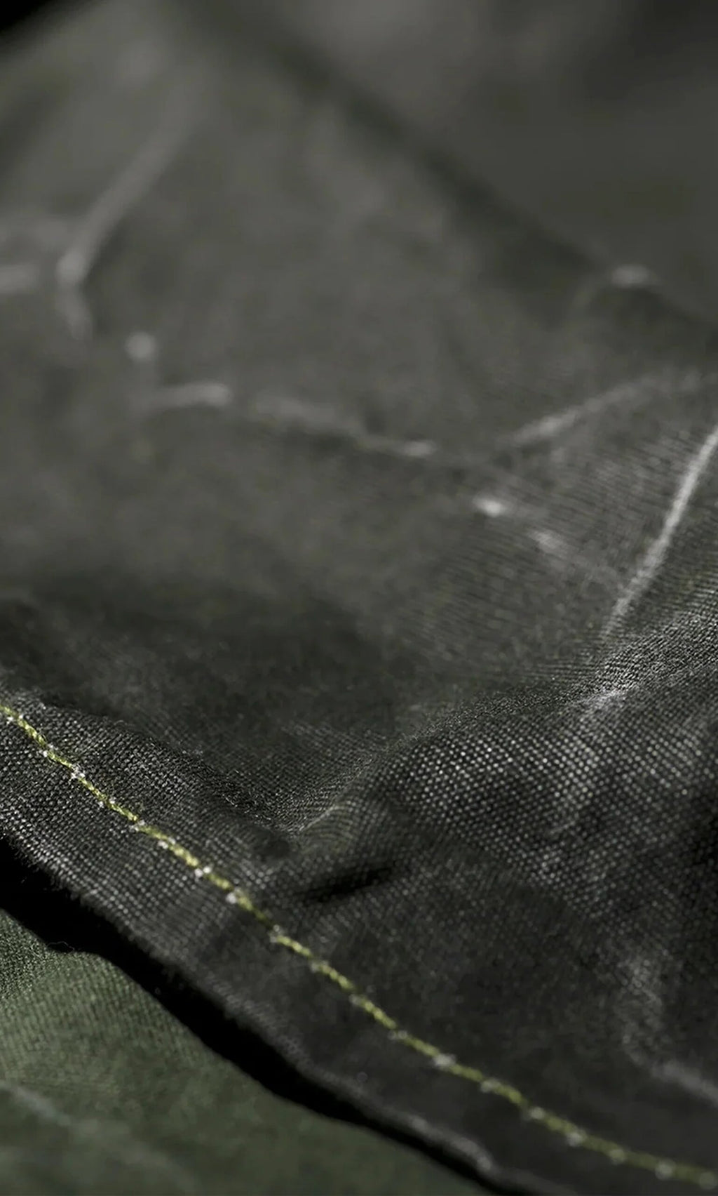 Plümo- Close-up of the Lumberjack Apron, crafted from black fabric with white chalk marks and green edge stitching.