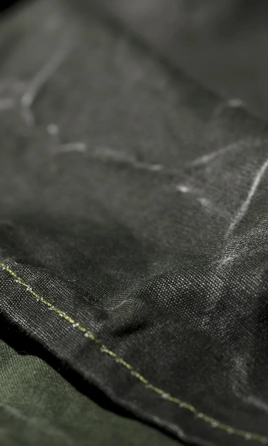 Plümo- Close-up of the Lumberjack Apron, crafted from black fabric with white chalk marks and green edge stitching.