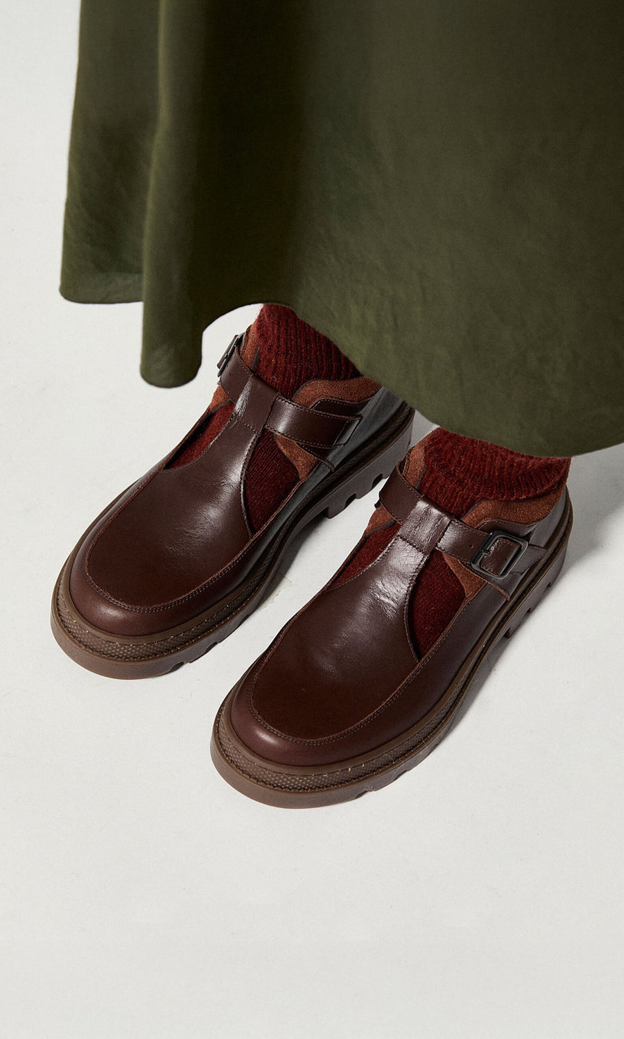 Plümo- Person wearing red socks and Toba Shoes with a grooved rubber sole, standing on a white surface.