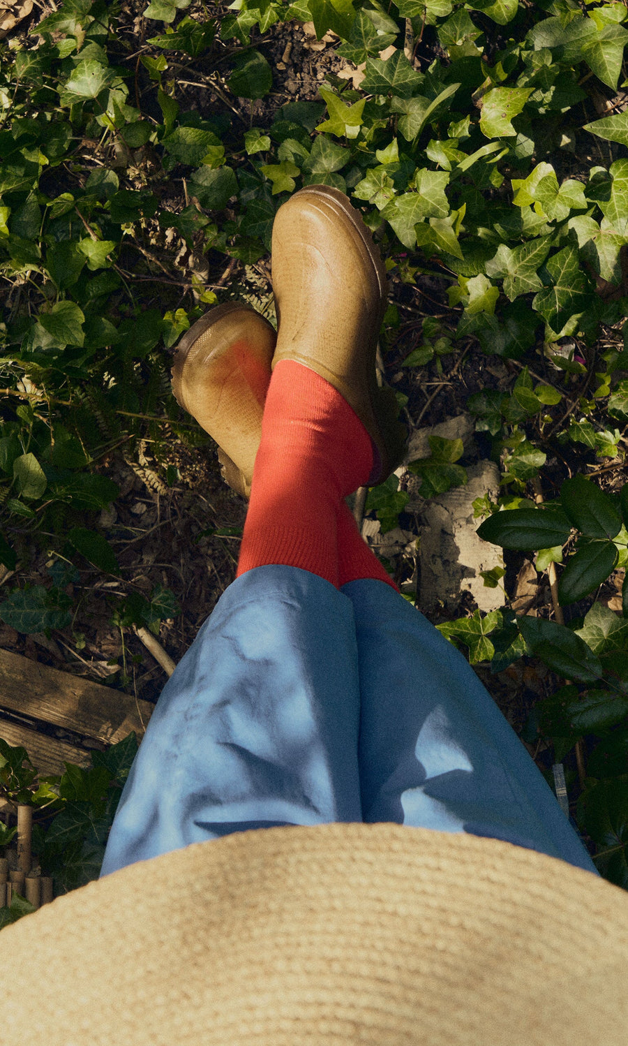 Plümo- Person in red socks, blue pants, and Opana Mules stands on ivy-covered ground, viewed from above.