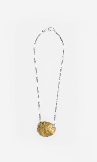 Plümo  Cressa Necklace: Artisan silver chain with a large flat gold brass pebble pendant on white background.