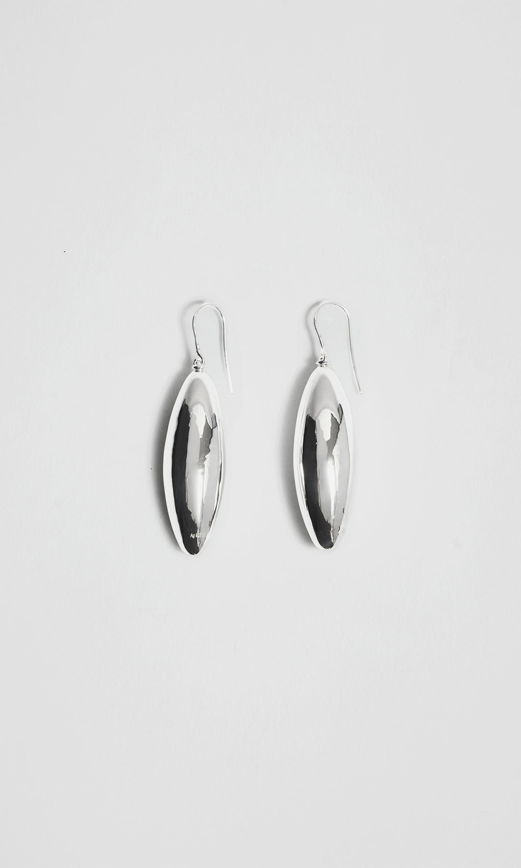 Plümo  Bea Drop Earrings: sculptural silver ovals with hooks, displayed on a plain white background.
