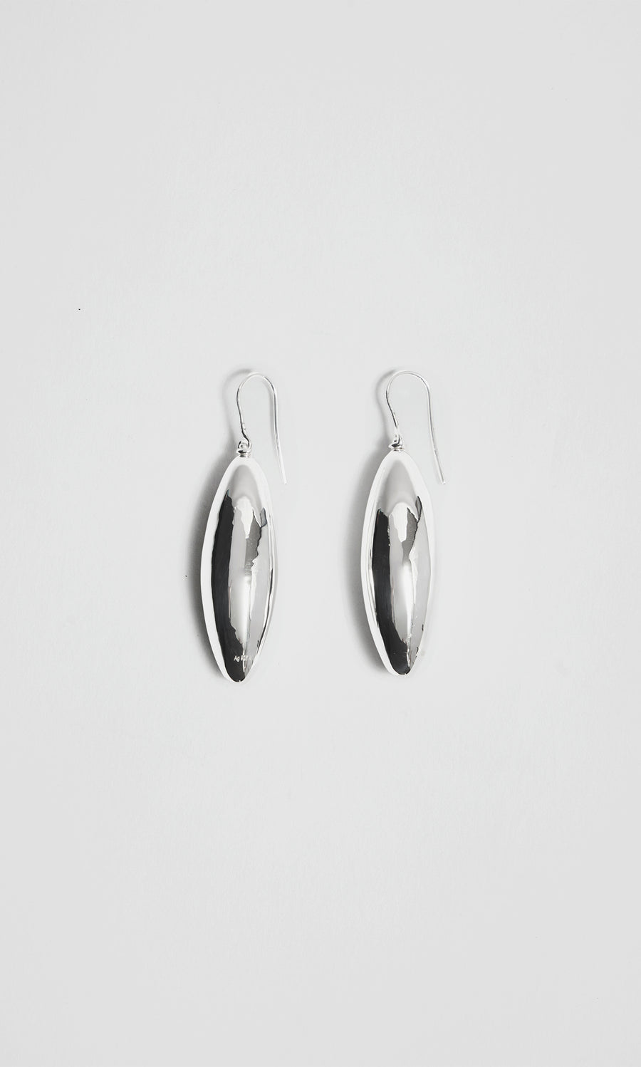 Plümo  Bea Drop Earrings: sculptural silver ovals with hooks, displayed on a plain white background.