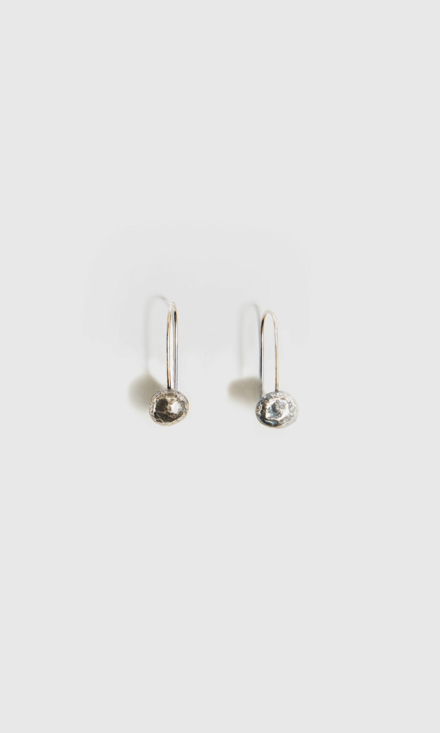 Plümo  Greta Earrings - Silver: minimalist moon drop design in recycled eco-silver, shown with studs on white background.