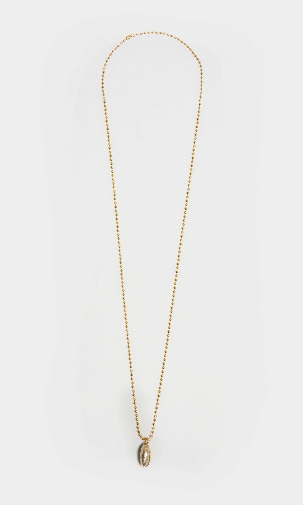 Plümo  Pistachio Pendant: Gold brass ball chain necklace with small oval pistachio pendant on white background.