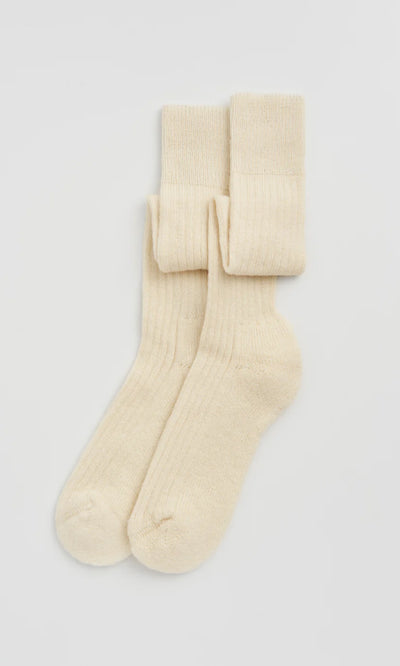 Plümo  Knee Socks - Clotted Cream: Ribbed wool knee socks with cushioned sole, cream-colored and neatly folded on white.