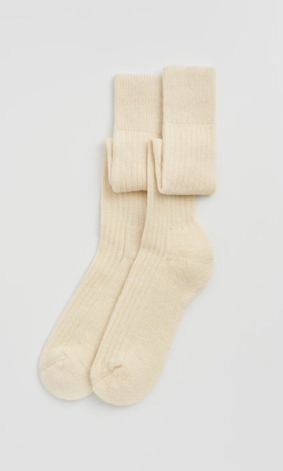 Plümo  Knee Socks - Clotted Cream: Ribbed wool knee socks with cushioned sole, cream-colored and neatly folded on white.