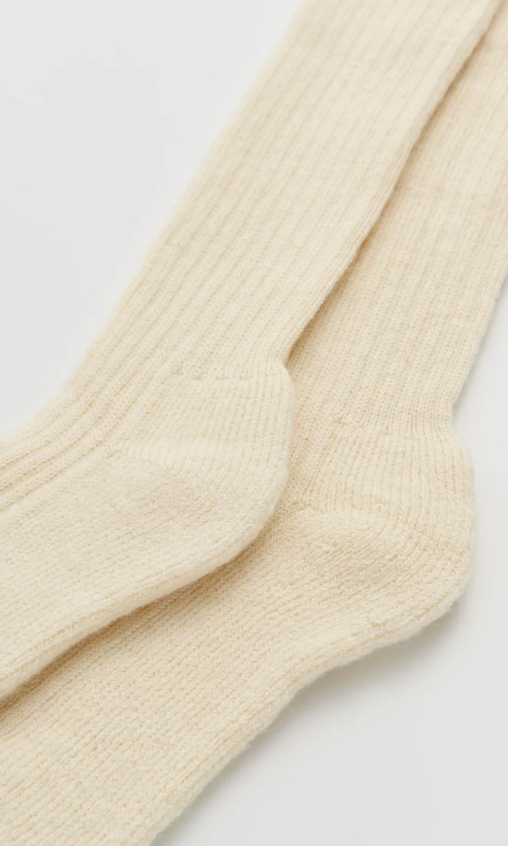 Plümo  Two Clotted Cream Knee Socks are laid flat, one slightly overlapping the other, on a white surface.