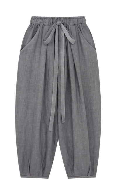 Plümo- Percival Linen Pants in gray feature balloon legs, elastic waist, front pockets, and a fabric tie on a white background.