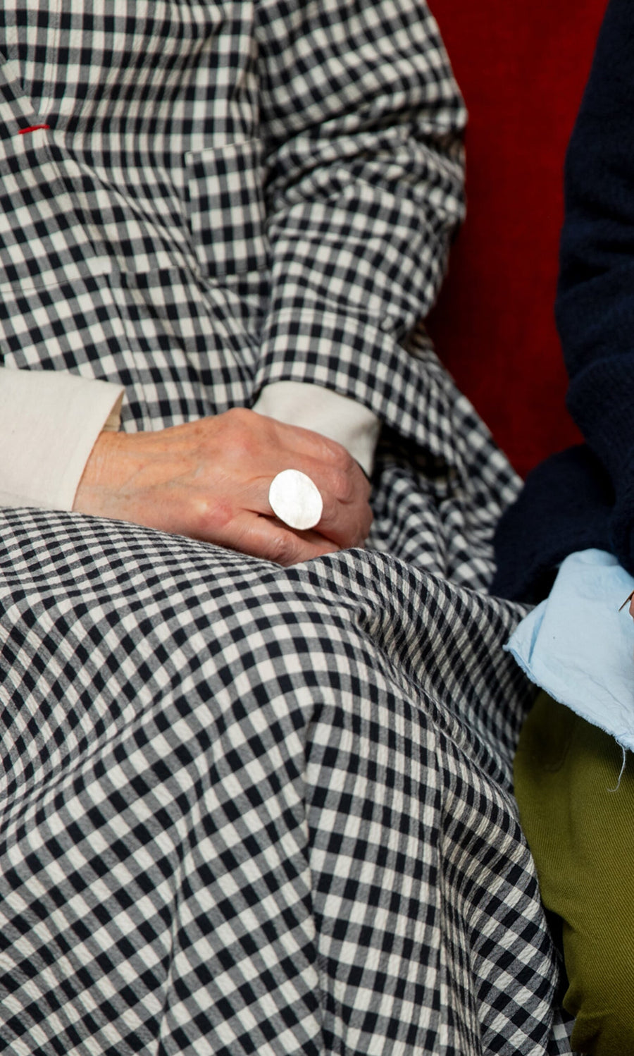 Plümo- A person in a checkered dress rests their hand, wearing the Eco Silver Pebble Ring, on their lap.