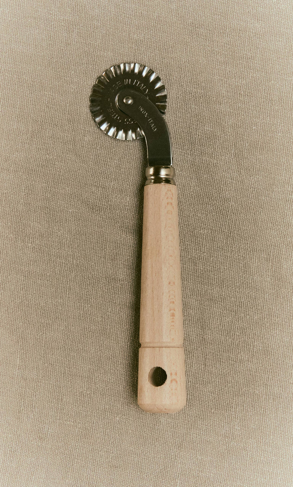 Plümo  Dough wheel with a fluted metal blade and a wooden handle.