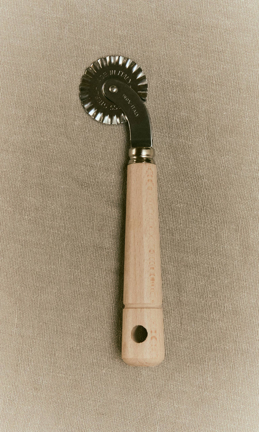 Plümo  Dough wheel with a fluted metal blade and a wooden handle.