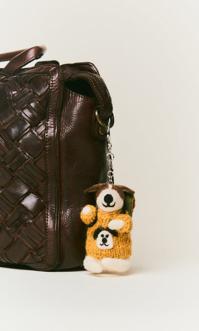Plümo  A brown woven leather bag with a Rambling Roger Keyring, handcrafted in Nepal, hanging from the handle.