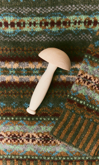 Plümo  Light-colored wooden Darning Mushroom resting on a patterned wool sweater.