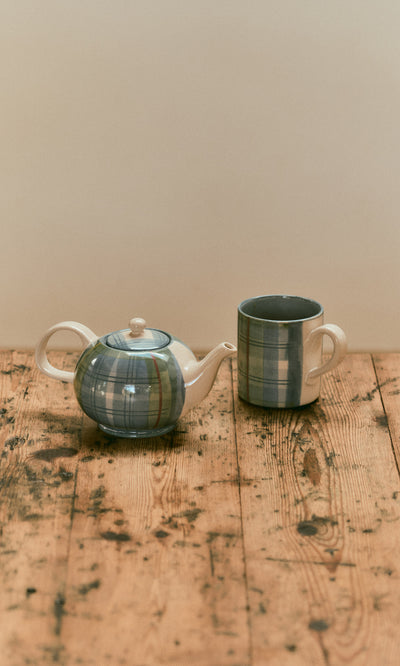 Plümo  A Tartan Teapot and matching mug with a blue tartan glaze sit on a wooden table.