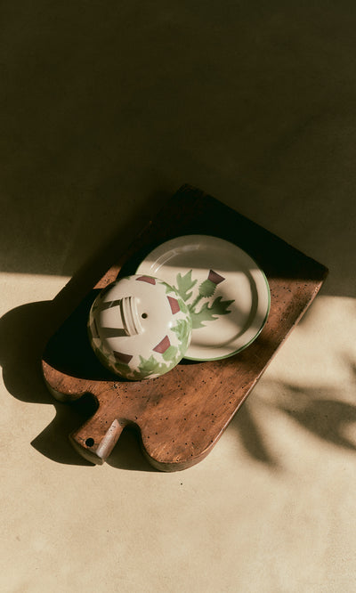 Plümo  The Thistle Cheese Dome sits on a wooden board, crafted from sustainable British clay, in sunlit gentle shadows.