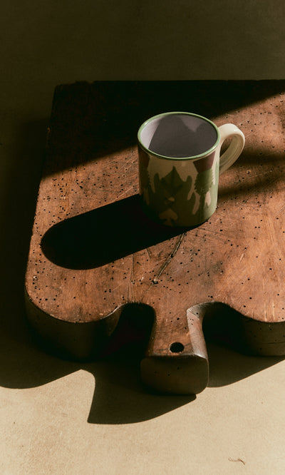 Plümo  The Thistle Mug casts a shadow on a rustic wooden cutting board in soft, warm light.