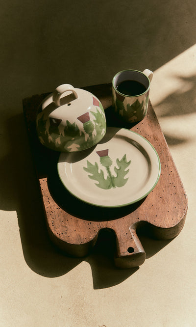 Plümo  Thistle Cheese Dome with matching plate and cup, hand-painted with green leaves and Scottish thistles in sunlight.