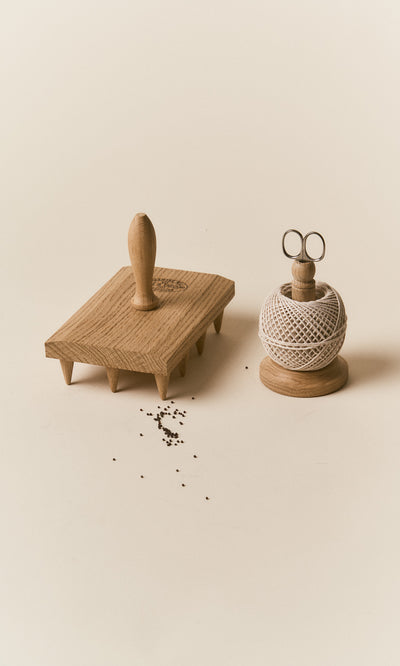 Plümo  An Oak String Tidy, wooden meat tenderizer, and scattered pepper on a beige background.