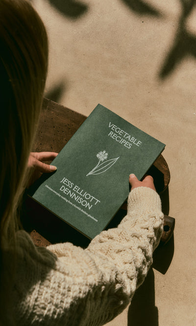 Plümo  Person holding Vegetable Recipes By Jess Dennison, a cookbook with seasonal vegetarian recipes.