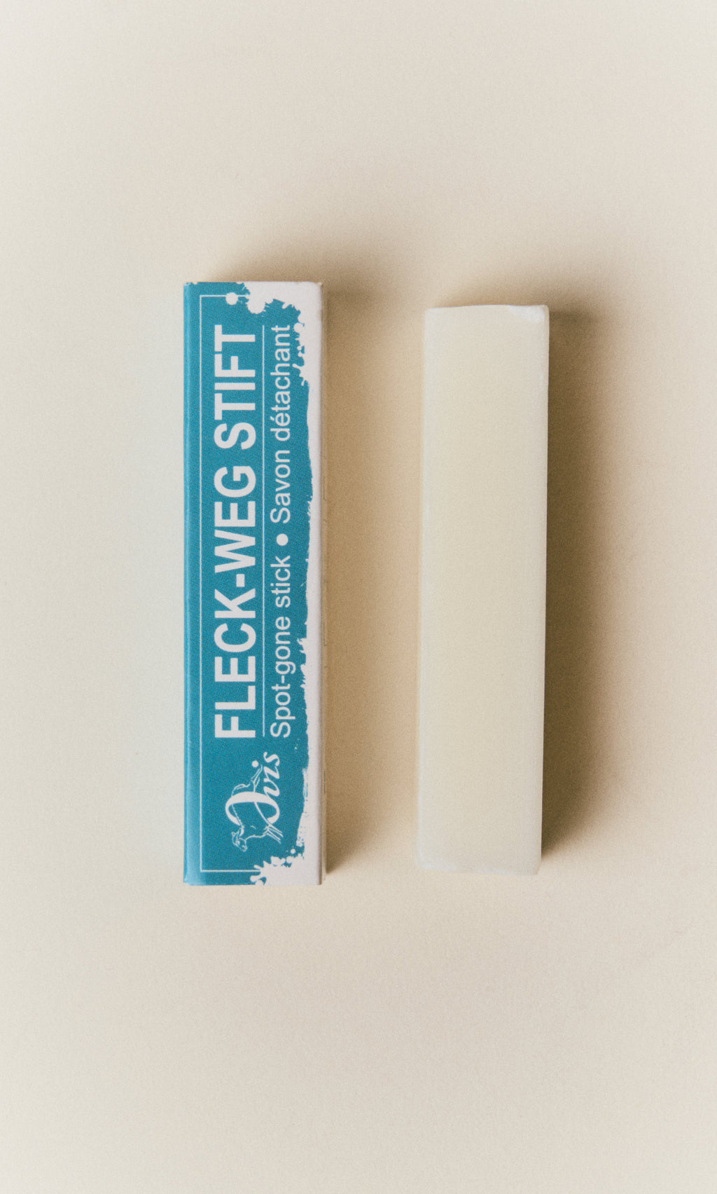 Plümo  A rectangular Stain Remover Stick next to its blue and white box.