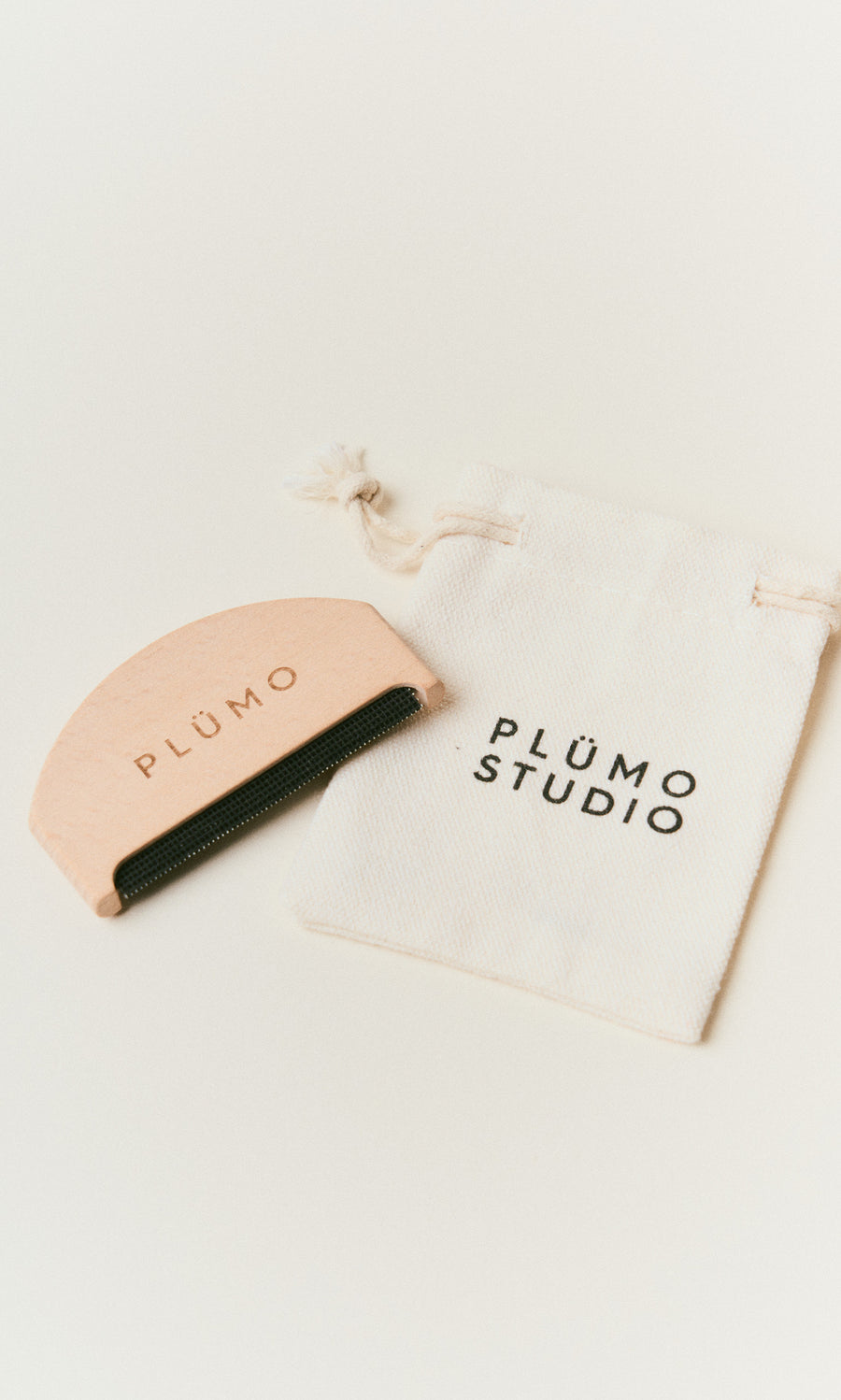 Plümo  A pink Wool Comb by PLÜMO rests with a PLÜMO STUDIO bag on a white surface.