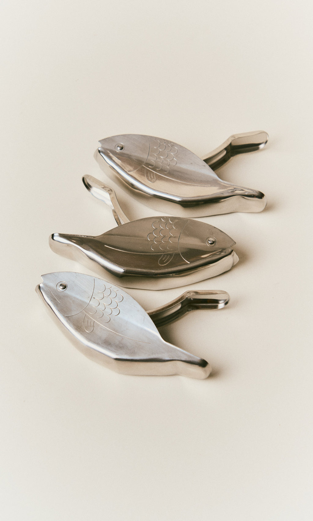 Plümo  Three metallic Fish Lemon Squeezer tools arranged diagonally.
